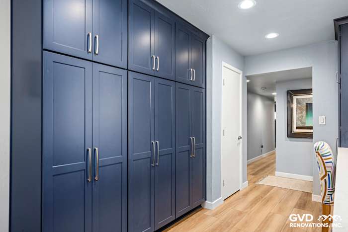 Navy blue kitchen cabinetry with sleek handles, modern hallway leading to open-concept kitchen in Fair Oaks