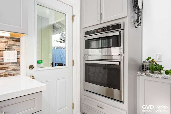 Modern kitchen design in Greenwood with stainless steel wall oven, quartz countertops, and light cabinetry