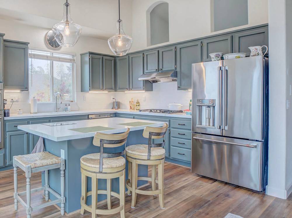 Modern kitchen featuring blue cabinetry, stainless steel appliances, and bright lighting