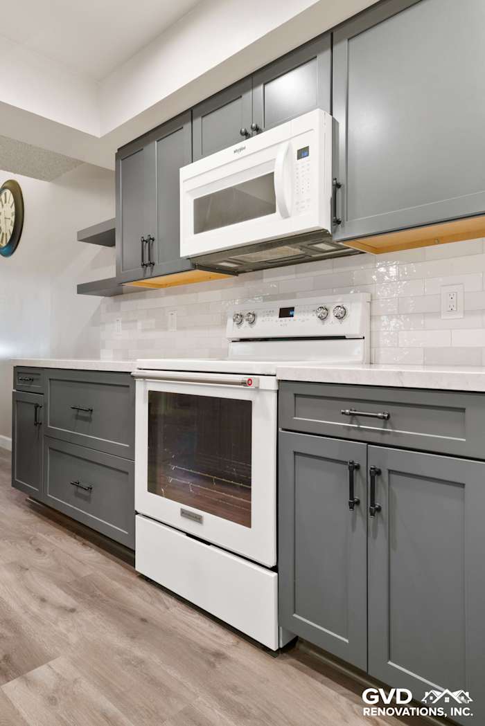 Modern kitchen remodel in Sacramento featuring gray cabinets, white appliances, and subway tile backsplash