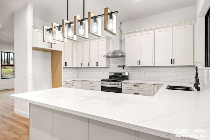Modern kitchen with white cabinets, quartz countertop, subway tile backsplash, and stylish pendant lighting