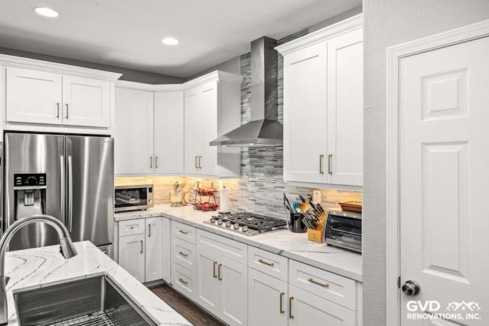 Modern kitchen featuring white custom cabinets, Cambria countertops, stainless steel appliances, and a stylish backsplash