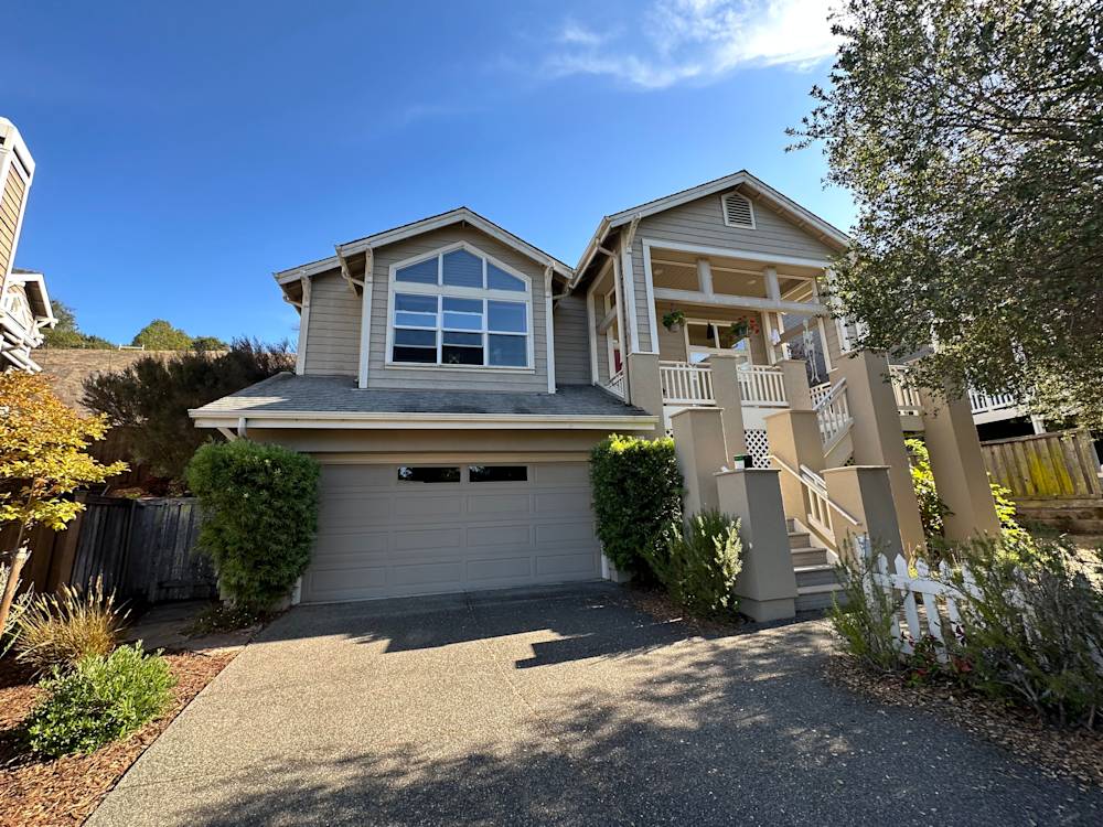 Two-story home in Madera, featuring light-colored siding and landscaped entrance with shrubs