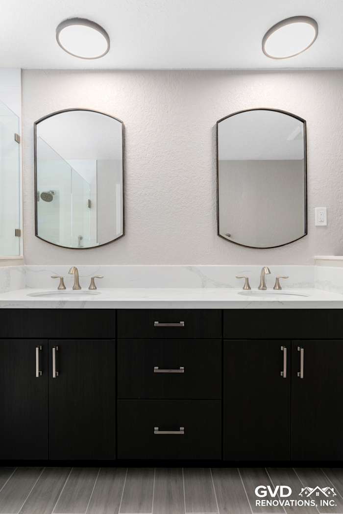 Modern master bathroom with dual mirrors, dark cabinetry, and sleek quartz countertops in Rocklin, CA
