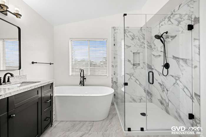 Modern bathroom featuring a freestanding bathtub, double sink vanity, and walk-in shower with marble tile