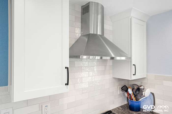 Sleek stainless steel hood over a modern kitchen stove with white cabinetry and subway tile backsplash in Fair Oaks