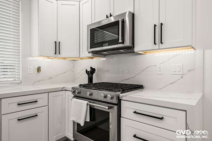 Modern kitchen in Antelope with white cabinetry, quartz countertop, stainless steel range, and stylish accents