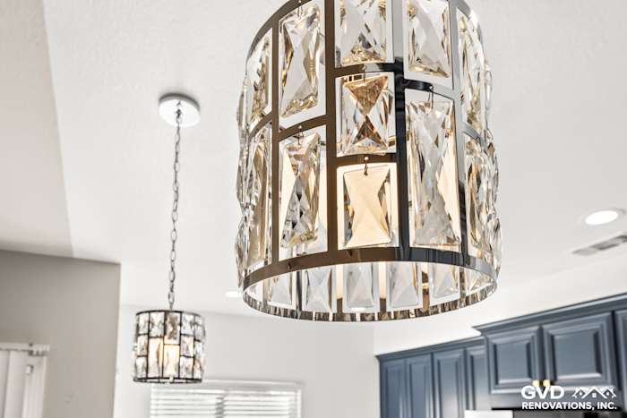 Crystal pendant light fixtures hanging above a stylish kitchen with navy blue cabinets in Sacramento