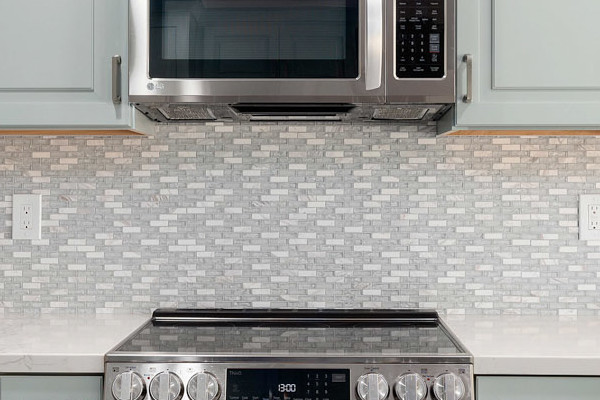 Modern kitchen remodel in Cameron Park featuring light green cabinets, stainless steel appliances, and quartz countertops