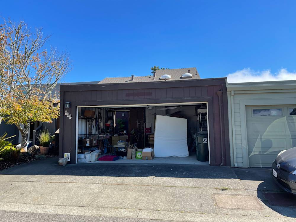 Cluttered garage area with gray walls and white backdrop in Sacramento neighborhood