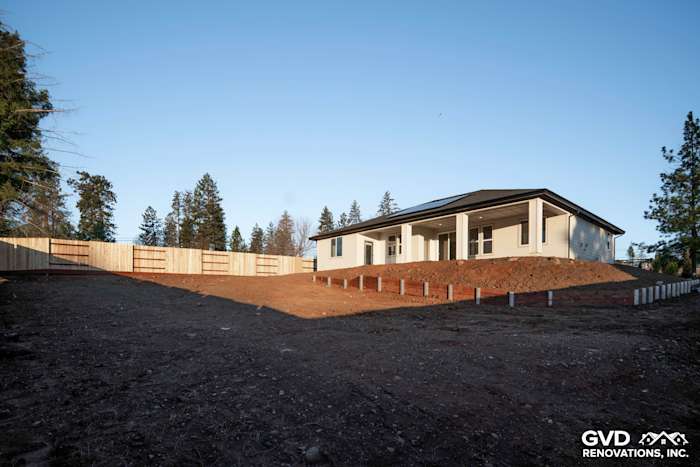 Rear view of a custom home in Paradise, CA, featuring a raised foundation and surrounding dirt yard