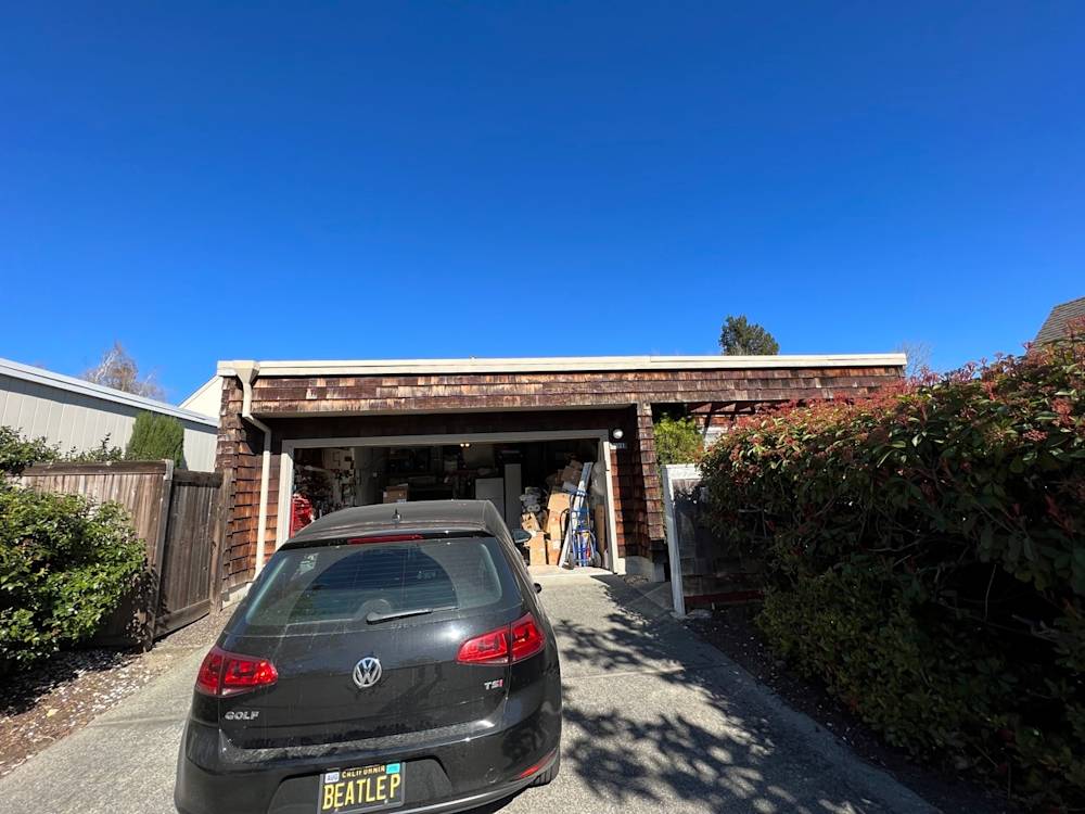 Wood-clad garage facade with cluttered driveway in Sacramento, under a clear blue sky