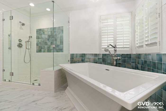 Bright bathroom with freestanding tub, teal tiled accent wall, and glass shower enclosure in Fair Oaks