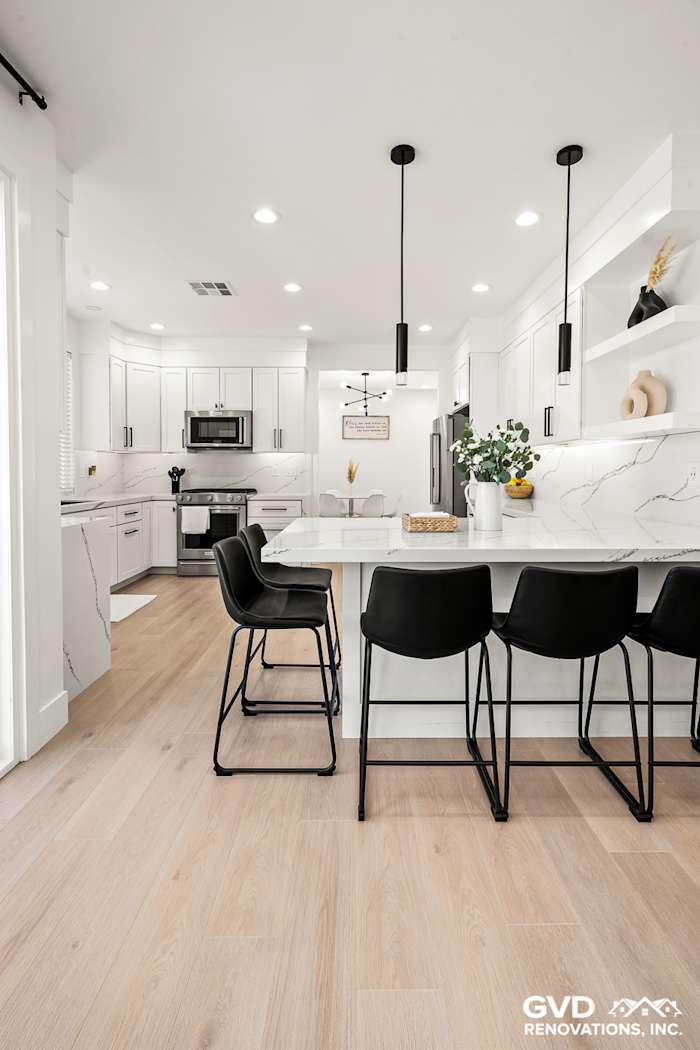 Modern kitchen remodel in Antelope featuring quartz countertops, white custom cabinets, and black bar stools