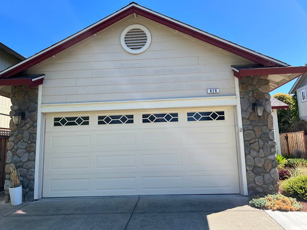 One-story home with stone accents, gray garage door, and light siding in Sacramento