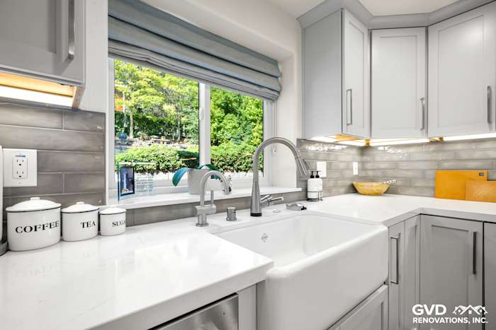 Updated kitchen sink area featuring a white farmhouse sink, gray cabinets, and modern fixtures in Rocklin, CA