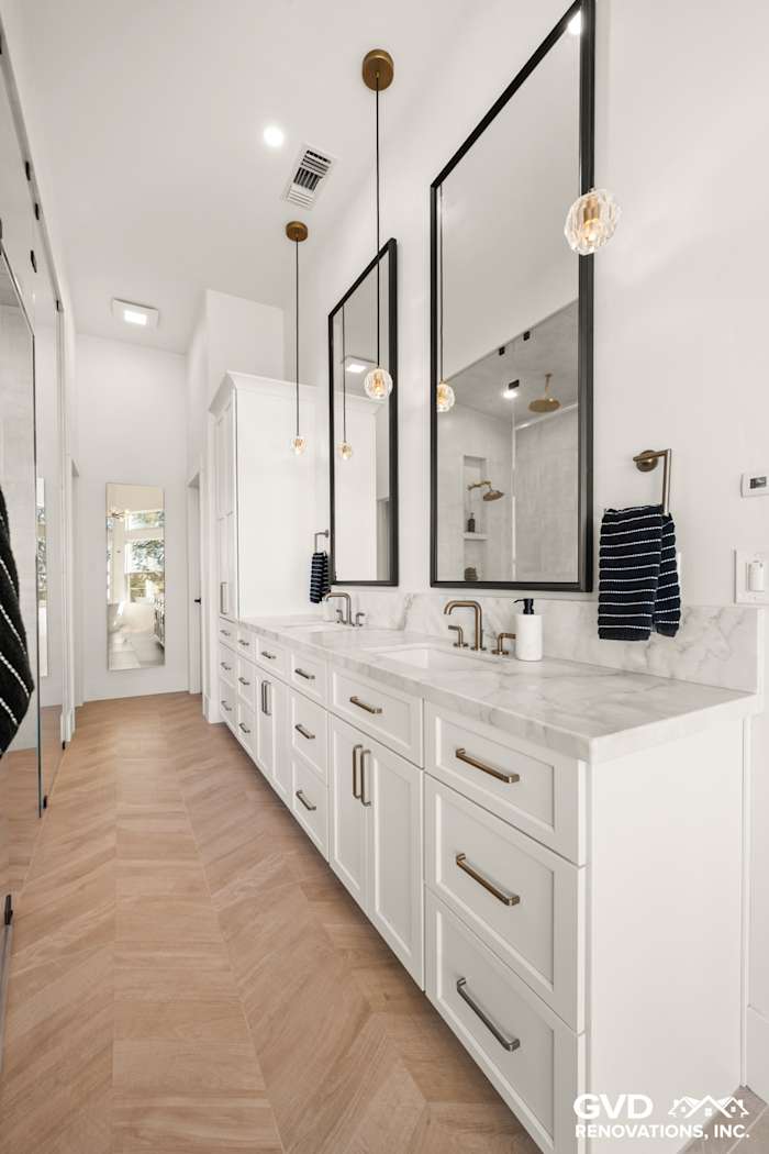 Luxurious master bathroom with dual mirrors, marble countertops, and herringbone wood flooring in El Dorado Hills