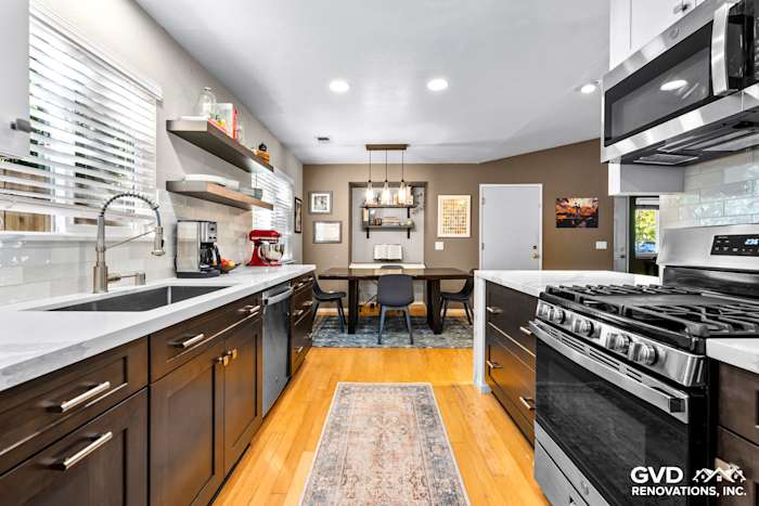 Modern kitchen remodel with white quartz countertops, dark cabinetry, stainless steel appliances, and a dining area in Davis