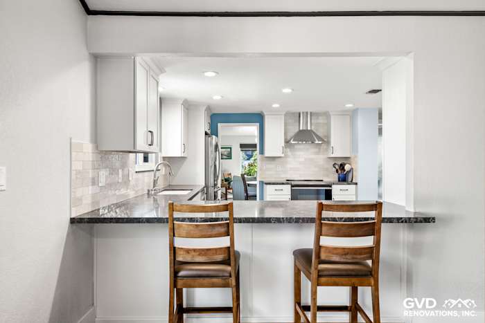 Modern Fair Oaks kitchen remodel featuring a spacious breakfast bar with wood stools, quartz countertops, and white cabinetry