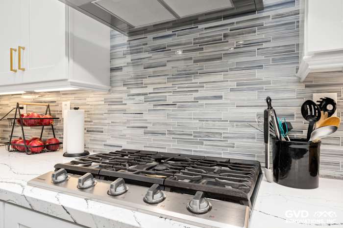 Gas stove with a sleek backsplash of gray and white glass tile in a modern kitchen