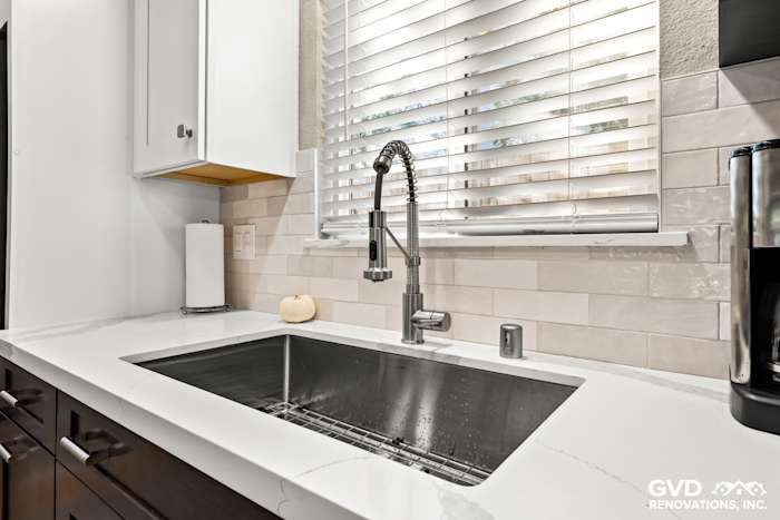Modern kitchen sink with stainless steel faucet, white quartz countertop, and subway tile backsplash in Davis, CA