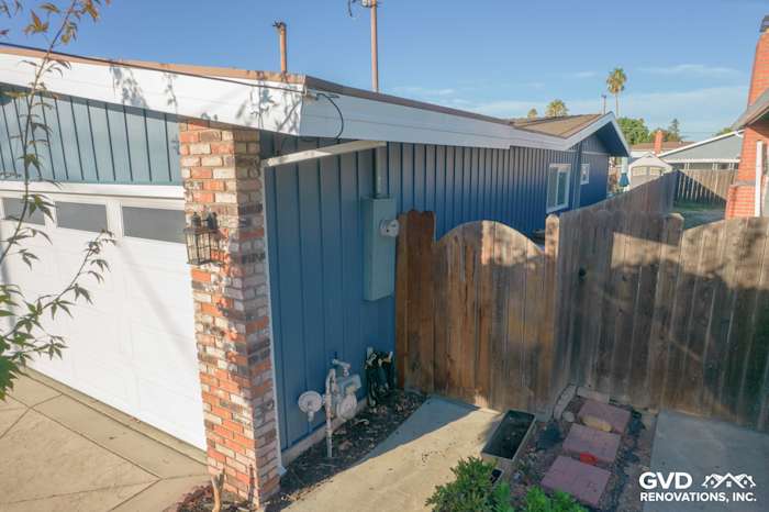 Close-up of home exterior featuring Prodigy Vinyl Siding in blue, brick accents, and wooden fence in Antioch