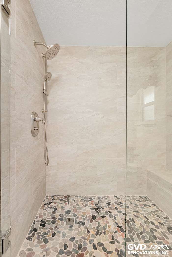 Spa-like shower featuring natural stone pebble floor and modern fixtures in renovated Fair Oaks bathroom