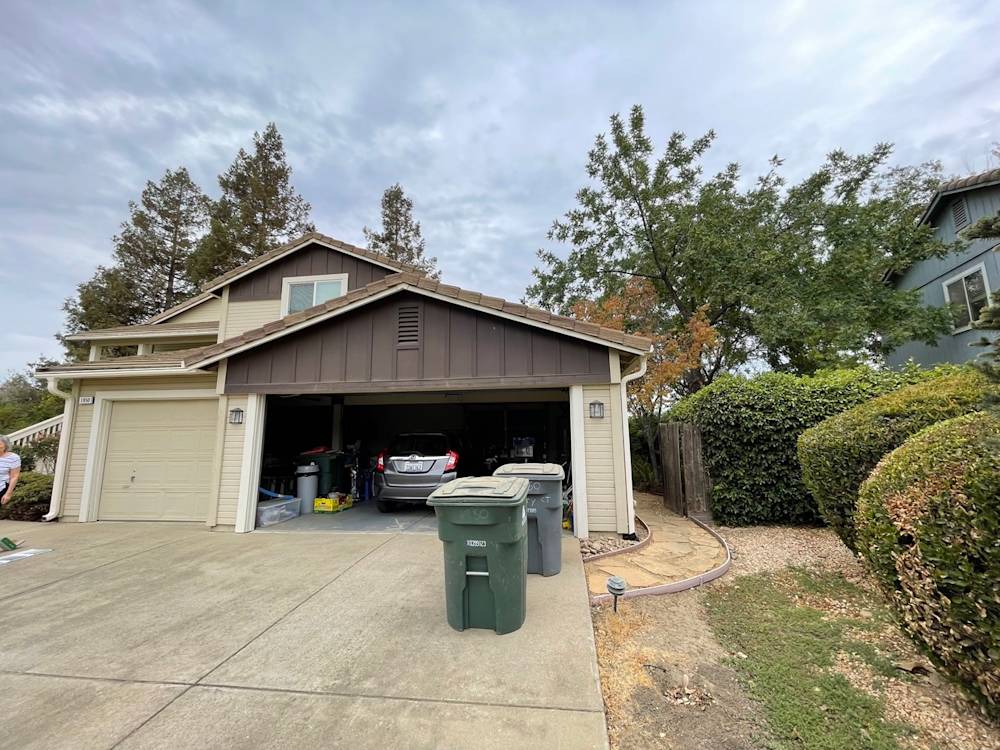Garage and driveway area in Sacramento, featuring an asphalt surface and lush landscaping