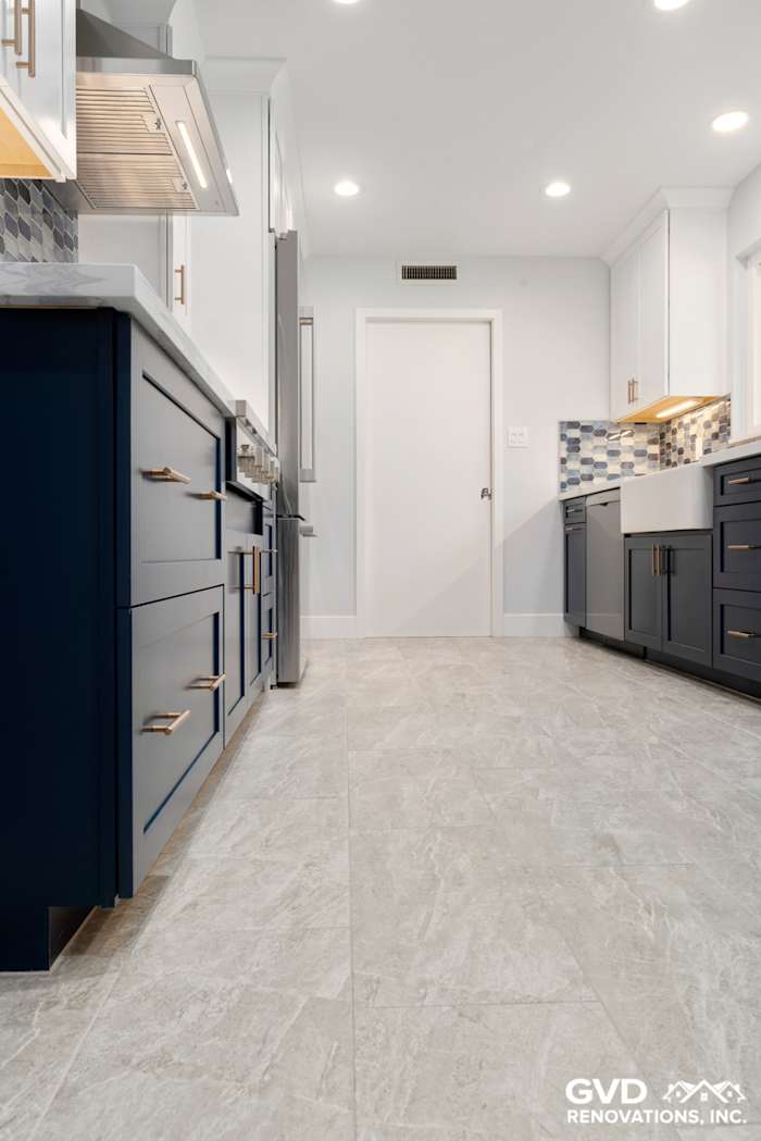 Modern kitchen remodel featuring navy blue cabinets, gray tile flooring, and stylish backsplash in Sacramento