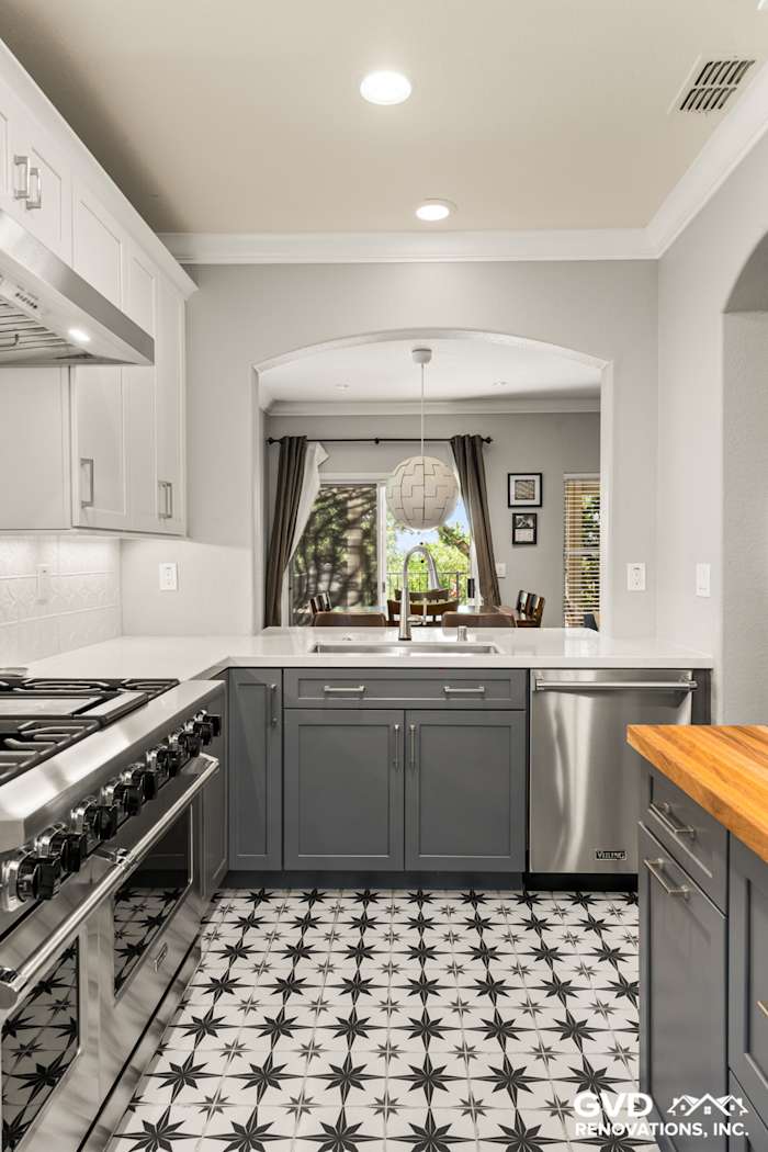 Modern kitchen featuring gray cabinets, stainless steel appliances, and patterned black and white tile flooring in Folsom