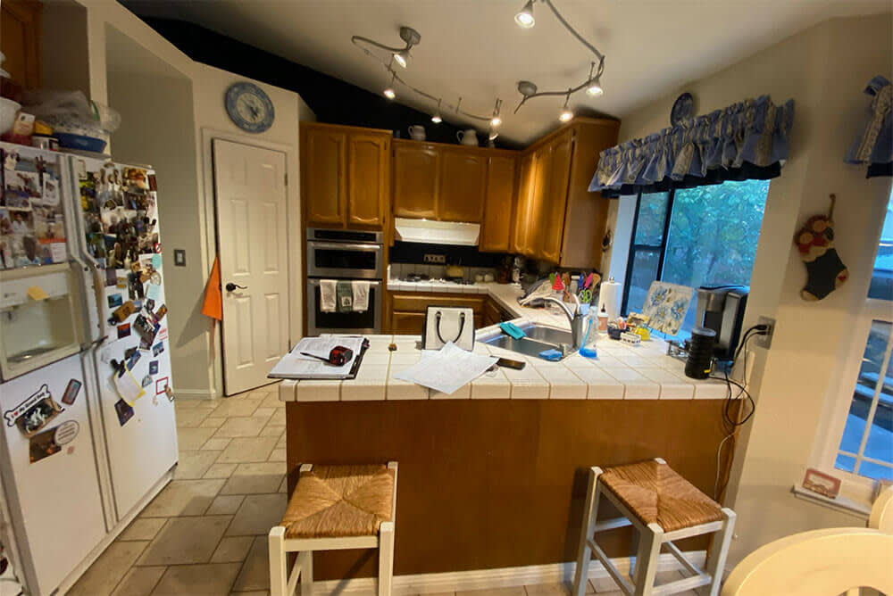 Dated kitchen with wooden cabinets, tile countertops, and cluttered layout