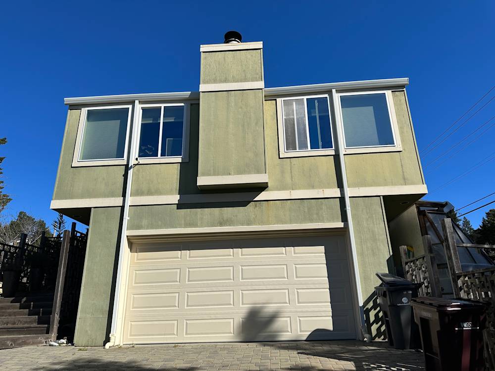Faded green exterior with large windows and a garage in Sacramento's Chelton neighborhood