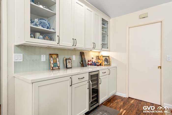 Custom white kitchen cabinets with glass doors, quartz countertop, and green backsplash in Carmichael remodel