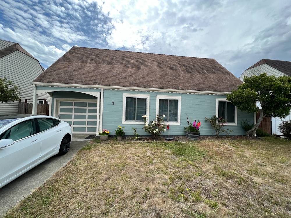 Charming blue home in Portola, Northern California with a sloped roof and a grassy front yard