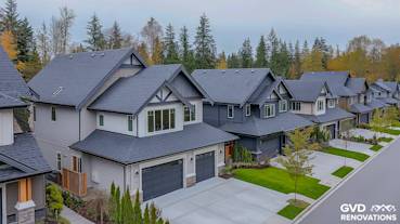 Newly installed dark shingles on multiple contemporary homes with landscaped yards in a suburban neighborhood