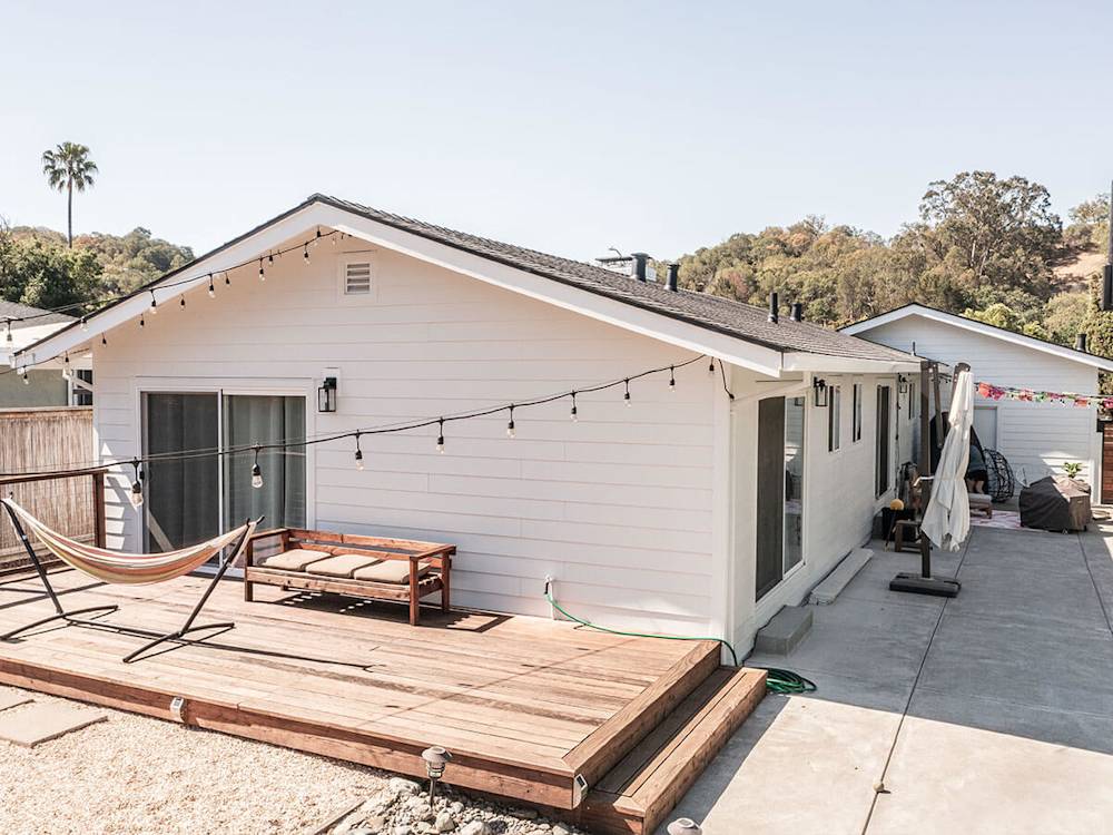 Updated white siding, modern deck, and stylish outdoor lighting create an inviting space