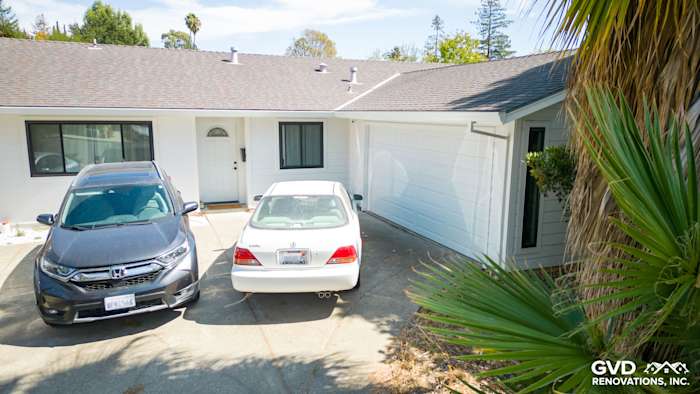 Updated home exterior featuring James Hardie Lap Siding in Arctic White with two parked cars and tropical landscaping