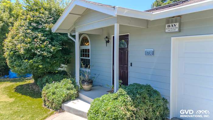 Cape Cod Gray composite cladding siding with new entryway, featuring a welcoming door and lush greenery