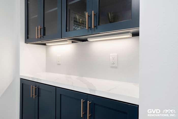 Modern kitchen remodel with navy blue cabinets, white marble countertop, and under-cabinet lighting in Sacramento