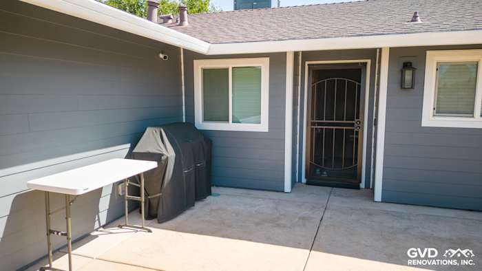 Modern home exterior featuring James Hardie Night Gray lap siding and Arctic White trim, with a grill and patio table