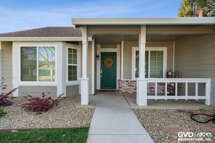 Folsom home exterior with Monterey Taupe HardiePlank siding and Arctic White trim, featuring a green door and landscaped yard