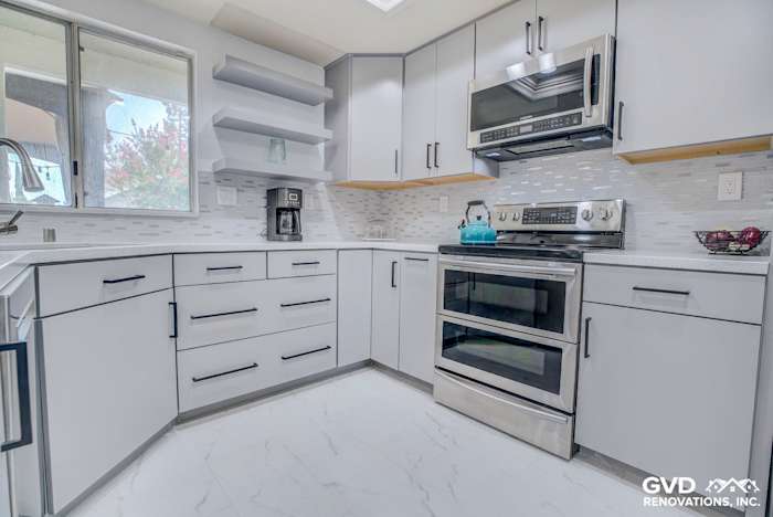 Modern kitchen remodel featuring white cabinets, sleek stainless steel appliances, and a marble-like floor in Sacramento