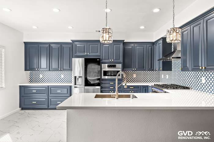 Modern kitchen featuring navy blue cabinets, white quartz countertops, and geometric backsplash tiles in Sacramento remodel