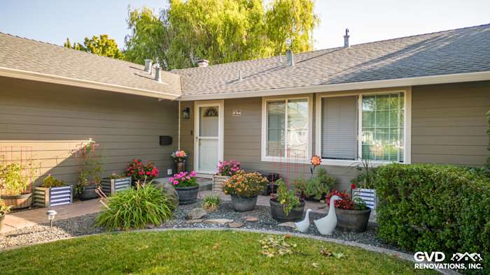 Home exterior featuring Timber Bark HardiePlank siding and Cobble Stone trim, surrounded by colorful flower pots