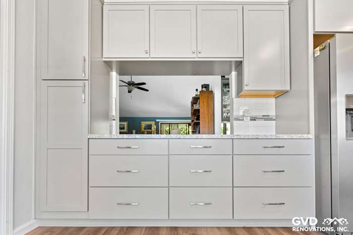 Modern kitchen with gray cabinets, quartz countertops, and open shelving, showcasing a bright and functional design
