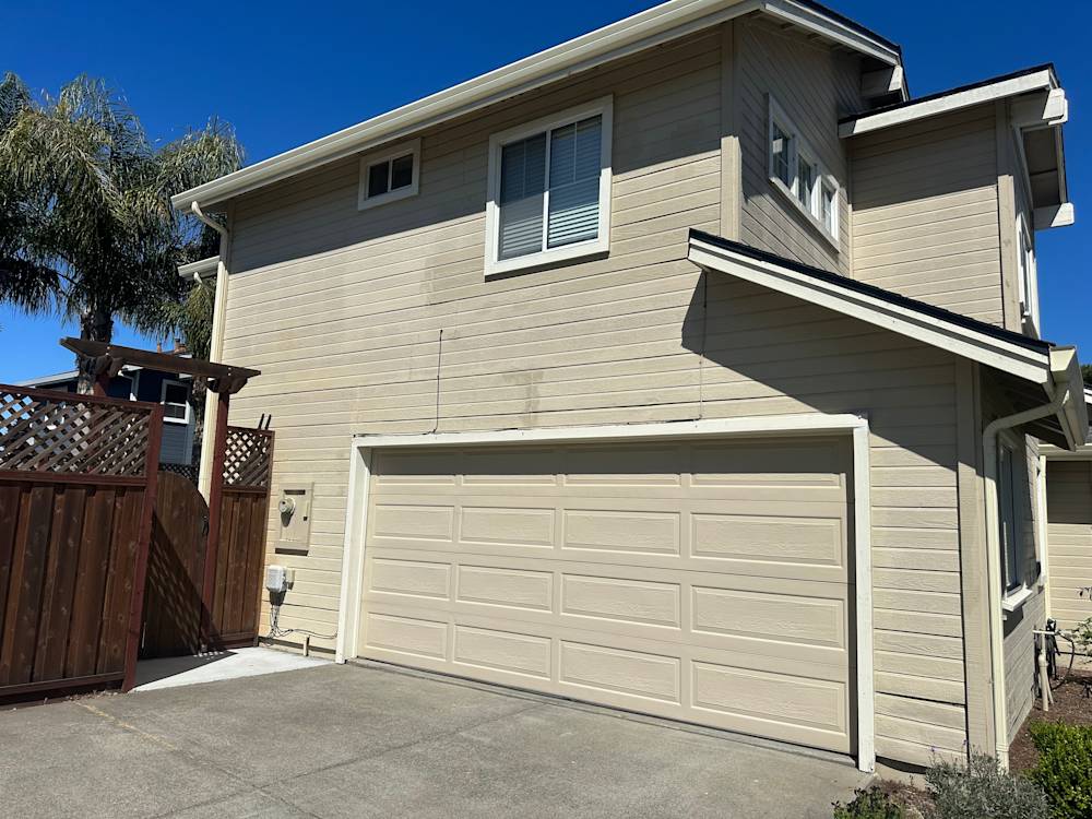 Two-story home exterior in Sacramento with beige siding and attached garage, featuring a wood fence