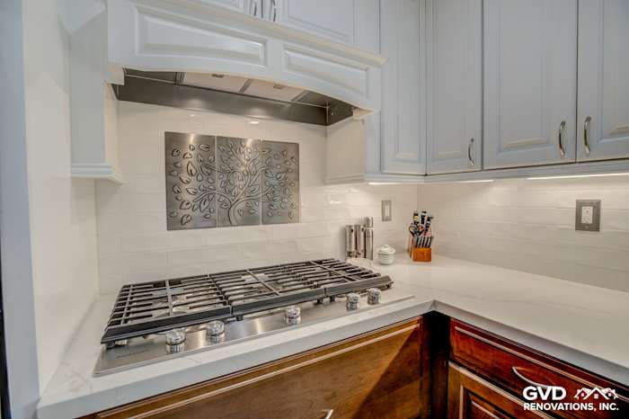 Modern kitchen corner with stainless steel gas range, white subway tile backsplash, and elegant wood cabinetry