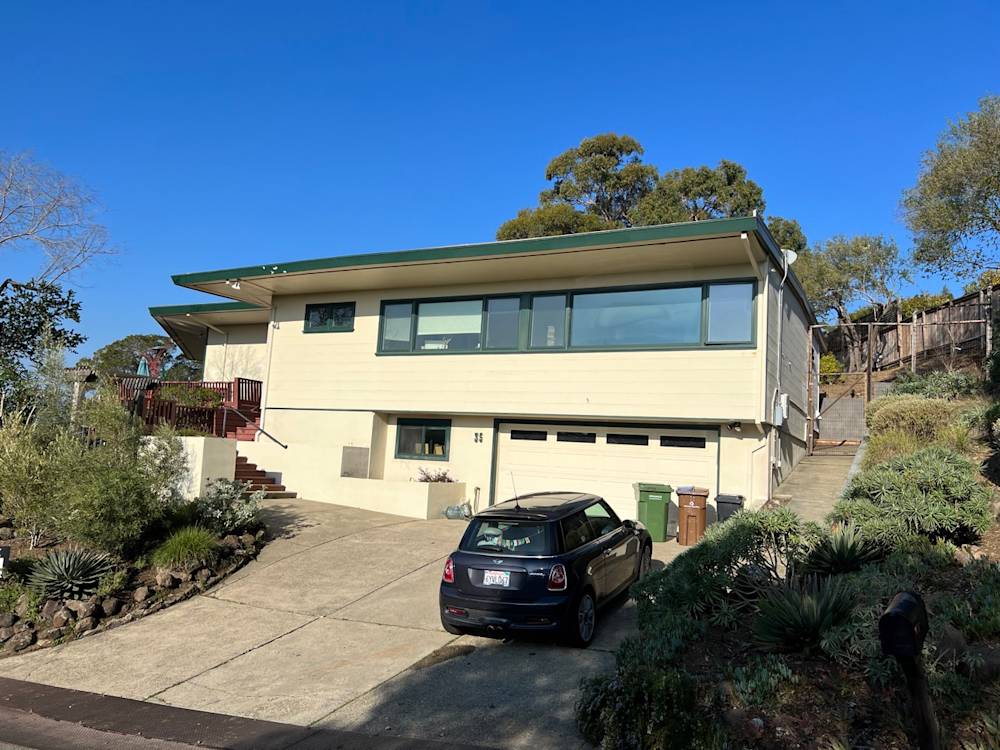 Modern two-story home in Sacramento with large windows, green roof, and landscaped driveway