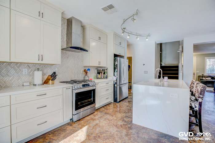 Modern kitchen remodel in Roseville featuring white cabinetry, quartz island, stainless steel appliances, and a herringbone