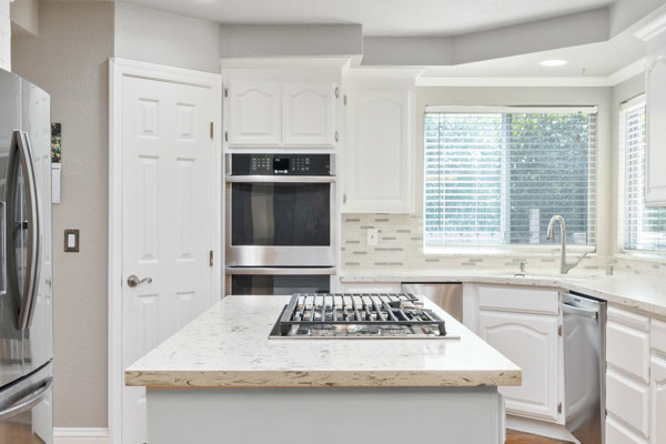 Modern kitchen with white cabinetry, quartz countertops, stainless steel appliances, and hardwood flooring in Fair Oaks, CA